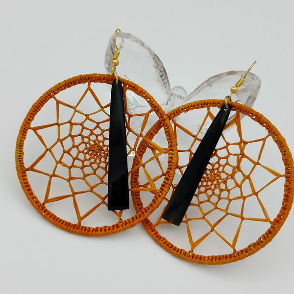 Boucle d'oreille type créole "Raffimendrika", bijoux artisanal, en corne de zébu foncée et raphia orange, mis en valeur